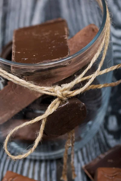 Glass jar with chocolate products. On black pine boards.