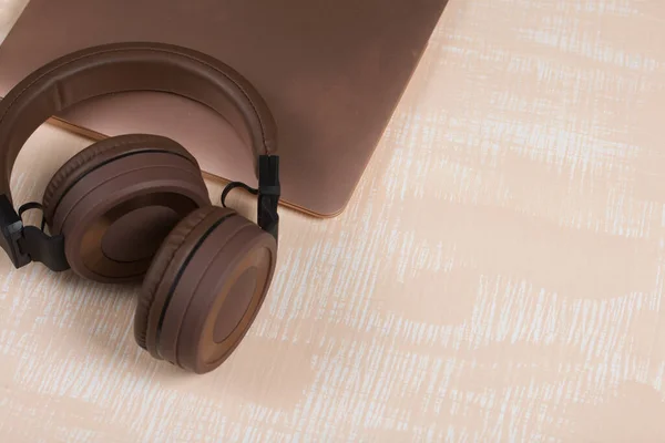 Fragment Pink Notebook Nearby Wireless Headphones Brown Surface Painted White — Stock Photo, Image