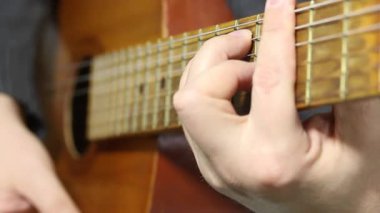 Bir adam altı telli akustik gitar çalar. Savaşta oynuyor. Çeşitli akorlar çalar.