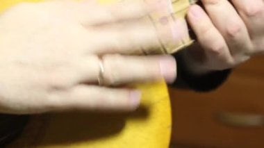 Bir adam altı telli akustik gitarla telleri çalar. Üst ve boyun yakın plan..