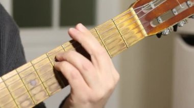 Bir adam altı telli akustik gitar çalar. Akort ister. Gitar fretboard 'unun ve akorların yakın çekim görüntüsü.