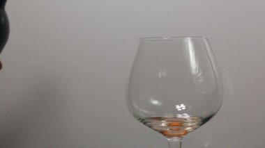Şarap A şişesinden bardağa dökülüyor. Camdan biraz döküldü. Yakın plan çekim. Cam arka planda döner..