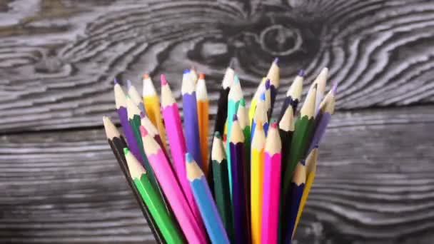 Färgade pennor i en pennhållare. Rotera mot bakgrund av svarta tavlor. Mannen tar ut flera pennor från den. Närbild. — Stockvideo