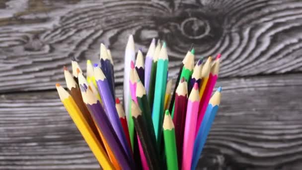 Kalem tutacağındaki renkli kalemler. Siyah çam tahtalarının arkaplanına göre döndür. — Stok video