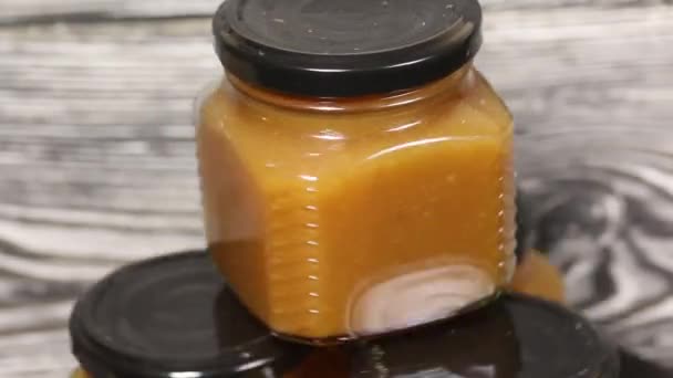 Marmellata in barattoli di vetro. Compilato da una piramide. Ruotare sullo sfondo di tavole di pino nero. La rotazione si interrompe gradualmente. — Video Stock