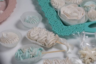 Çubukta Zephyr. Farklı şekillerde ve gölgelerde şekerlemeler. Yakın plan çekim. Beyaz bir masa ve turkuaz bir tepside..