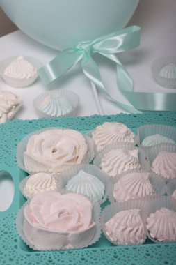 Çubukta Zephyr. Farklı şekillerde ve gölgelerde şekerlemeler. Yakın plan çekim. Beyaz bir masa ve turkuaz bir tepside..