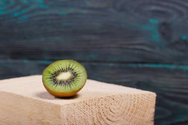 Kivi meyvesi ikiye bölünmüş. Sulu yeşil et görünür. Tahta bir blokta yatıyor.