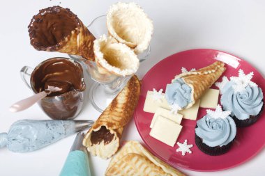 Krem peynirli kek. Marshmallow kar tanesi ile süslenmiş. Hazırlıkları için yakın waffle konileri ve malzemeler.