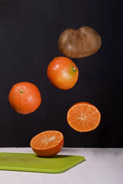 Tangeriner Och Kiwis Flyter Ovanför Bordsytan Vissa Sönderskurna Levitation Frukt — Stockfoto