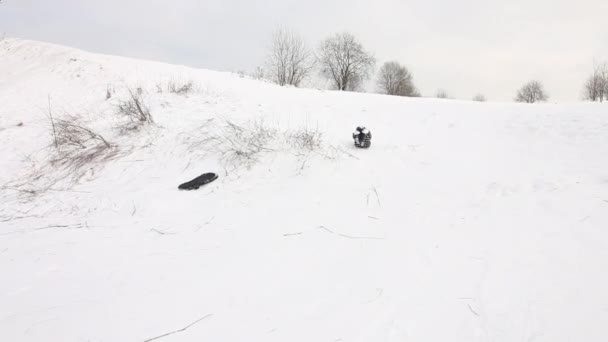 Dziewczyna siada na sankach i zjeżdża ze śnieżnego wzgórza. Zjeżdżalnie, upadki i rolki szybko. — Wideo stockowe