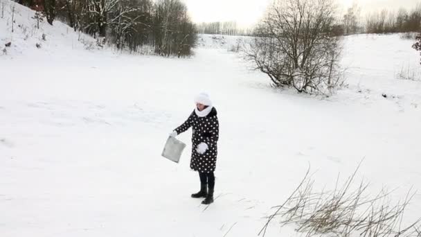 La chica sube a una colina cubierta de nieve con un trineo para cabalgar hasta el fondo de la colina.. — Vídeos de Stock