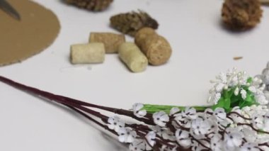 Kadın bir koni çelengi topluyor. Karton ve kağıttan yapılmış bir yüzüğe yapıştırıcı kozalakları. Yapıştırıcı tabancasıyla