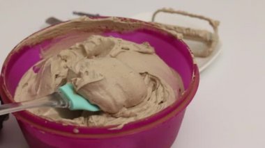 Bir kadın kurabiye ve kremayla pasta yapar. Kalıba kurabiye koyar ve kremayla kaplar..