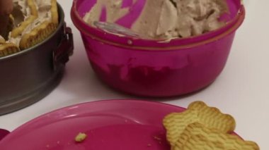 Bir kadın kurabiyelerden pasta yapar. Kremayı kurabiyelerin üzerine yay. Yakınlarda bir tabakta kurabiye var..