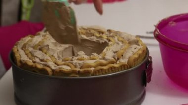 Bir kadın kurabiyelerden pasta yapar. Kremayı kurabiyelerin üzerine yay. Tabakta kurabiyeler var. Yakın çekim..