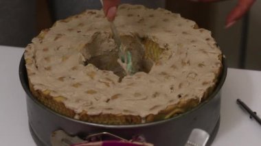 Bir kadın kurabiyelerden pasta yapar. Kurabiyelerin üzerine krema sürüyor. Forma girdi. Yakın çekim..