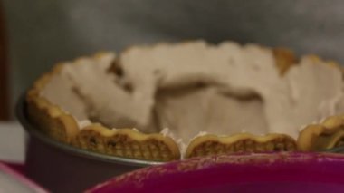 Bir kadın kurabiye ve kremayla pasta yapar. Kalıba kurabiye koyar ve kremayla kaplar. Sırada kek kurabiyeleri var..