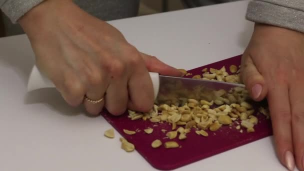 Frau hackt geröstete Erdnüsse mit Messer. Zum Bestreuen von Sahnetorten — Stockvideo