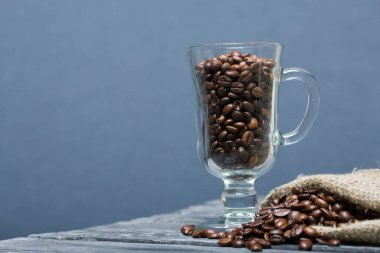 Kahve çekirdeği. Cam bardağa ve keten poşete doldurulmuş. Yakın çekim..