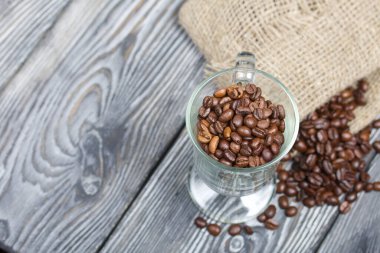 Kahve çekirdeği. Cam bardağa ve keten poşete doldurulmuş. Yakın çekim..