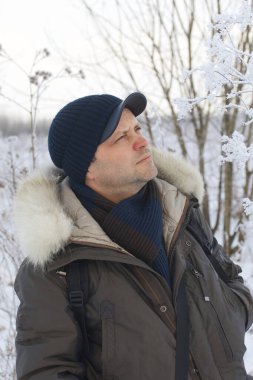 Kış parkındaki bir adamın portresi. Etrafta çok kar var, bitkiler buzla kaplı..