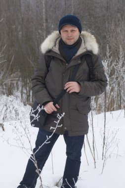 Kış parkındaki bir adamın portresi. Etrafta çok kar var, bitkiler buzla kaplı..