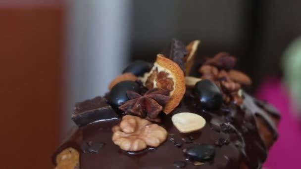 Banánový chléb zdobený roztavenou čokoládou, ořechy a sušeným ovocem. Otočí se na jevišti. Detailní záběr glazury a dekorací. — Stock video