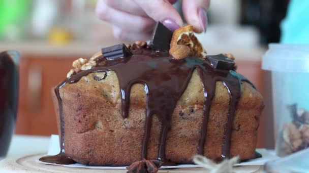 La mujer decora pan de plátano. Coloca los ingredientes en el chocolate derretido. Primer plano de disparo. — Vídeos de Stock