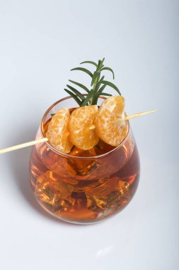 Alkolik kokteyl. Biberiye dilimleri ve mandalina dilimleriyle süslenmiş. Beyaz bir arka planda. Yakın çekim..