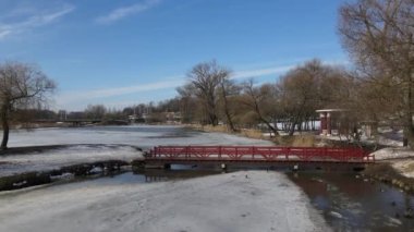 Loshitsa Park, Minsk, Belarus 'taki ahşap köprüden uçuş. Kamera adaya giden köprünün üzerinden uçuyor. Kış manzarası.