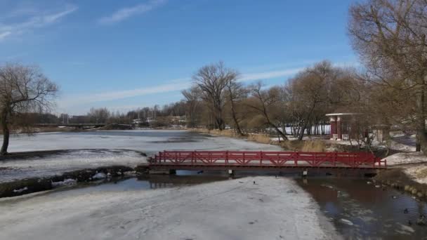 Vuelo sobre el puente de madera en Loshitsa Park, Minsk, Bielorrusia. La cámara vuela sobre el puente que conduce a la isla. Paisaje invierno. — Vídeos de Stock