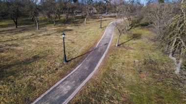 Şehir parkında uçuş. Aşağıda bir yaya geçidi görünüyor. Uzakta yüksek binalar var..