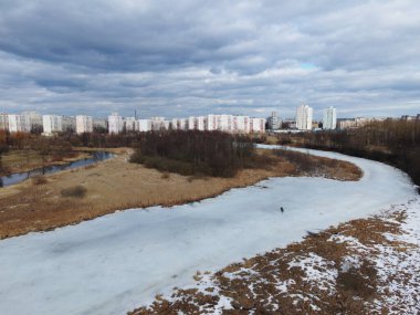 Nehrin üzerinden bahar parkına uçacağız. Buz kalıntıları görülebilir. Uzakta, insanlar sokaklarda yürüyorlar..