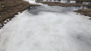 Nehrin üzerinden bahar parkına uçacağız. Buz kalıntıları görülebilir. Uzakta, insanlar sokaklarda yürüyorlar..