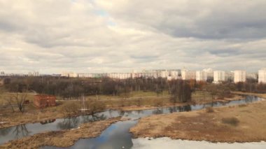 Nehrin üzerinden bahar parkına uçacağız. Kar kalıntıları bazı yerlerde görülebilir. Bahar manzarası. Ufukta çok katlı binalar görünüyor..