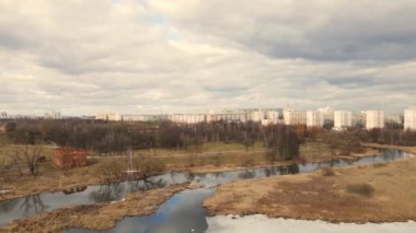 Nehrin üzerinden bahar parkına uçacağız. Kar kalıntıları bazı yerlerde görülebilir. Bahar manzarası. Ufukta çok katlı binalar görünüyor..