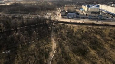 Spring City Parkı üzerinde uçuş. Yürüme yolları görülebilir. Park sokakları desenleri. Ufukta yüksek binalar ve bir fabrika var. Loshitsa Parkı, Minsk, Belarus.