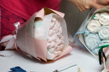 Bir kadın ambalaj kağıdında zephyr buketleri paketliyor. Zephyr 'den laleler ve güller.