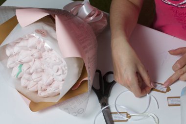 Bir kadın ambalaj kağıdında zephyr buketleri paketliyor. Zephyr 'den laleler ve güller.