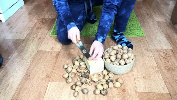 Der Mann knackt Walnüsse. Schläge mit dem Hammer auf einen Holzklotz — Stockvideo