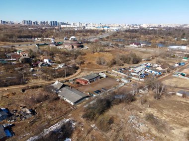 Şehir manzarasının havadan görünüşü. Ufuktaki yüksek binalar. Ön planda bir katlı evler var. Nehir görünüyor..