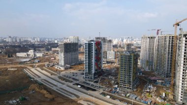Geniş bir yerleşim alanı inşaatı. İnşaat alanı görünür durumda. Çok katlı binalar ve altyapı yapım aşamasında. İnşaatın hava fotoğrafçılığı.