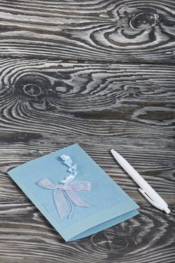 El yapımı tebrik kartı. Yakınlarda tükenmez kalem var. Çam ağacının üzerinde yatıyor.