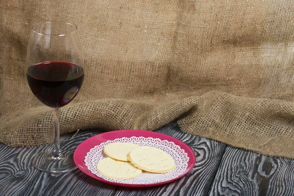 A glass of dry red wine and unleavened bread on a plate. Celebration of the Lord\'s Supper.