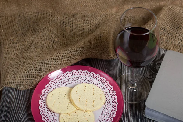 A glass of dry red wine and broken unleavened bread lie on a plate. To celebrate the Lord\'s Supper. Nearby lies the Bible.