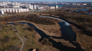 Baharda şehir parkının üzerinden uçacağız. Buz kalıntılarının olduğu nehir görülebilir. Uzakta çok katlı şehir binaları var..
