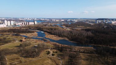 Baharda şehir parkının üzerinden uçacağız. Buz kalıntılarının olduğu nehir görülebilir. Uzakta çok katlı şehir binaları var..