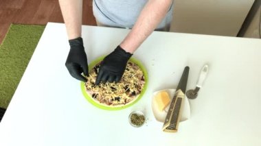 Adam pizzanın üzerindeki peyniri düzeltir. Evde pizza yapmak..