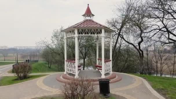 Şehir parkında çardağın içinden uçuyor. Yakınlarda bir bisiklet yolu var. Çiçeksiz bahar parkı. — Stok video